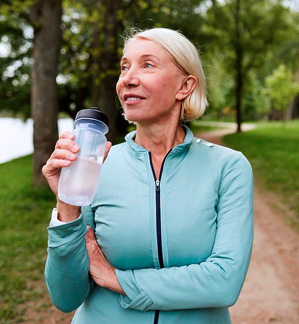 Ältere Joggerin macht Pause und trinkt Wasser