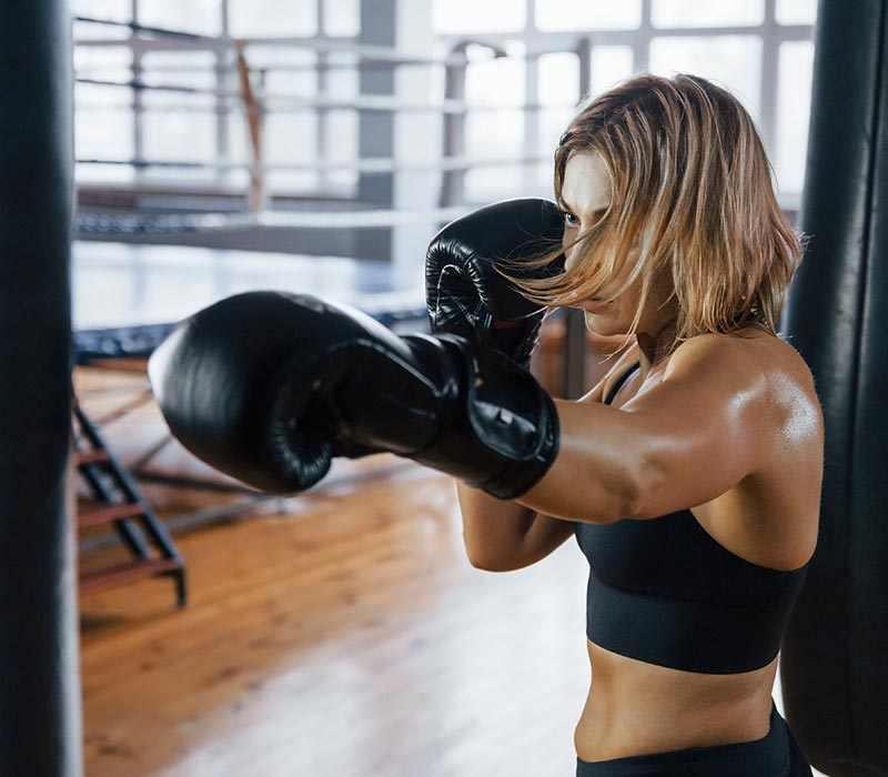 Boxerin trainiert am Sandsack im Boxclub