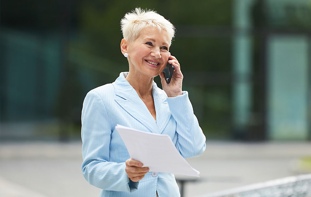 Coach beim Telefonat mit Unterlagen in der Hand