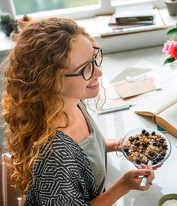 Frau isst Müsli mit Heidelbeeren im Büro