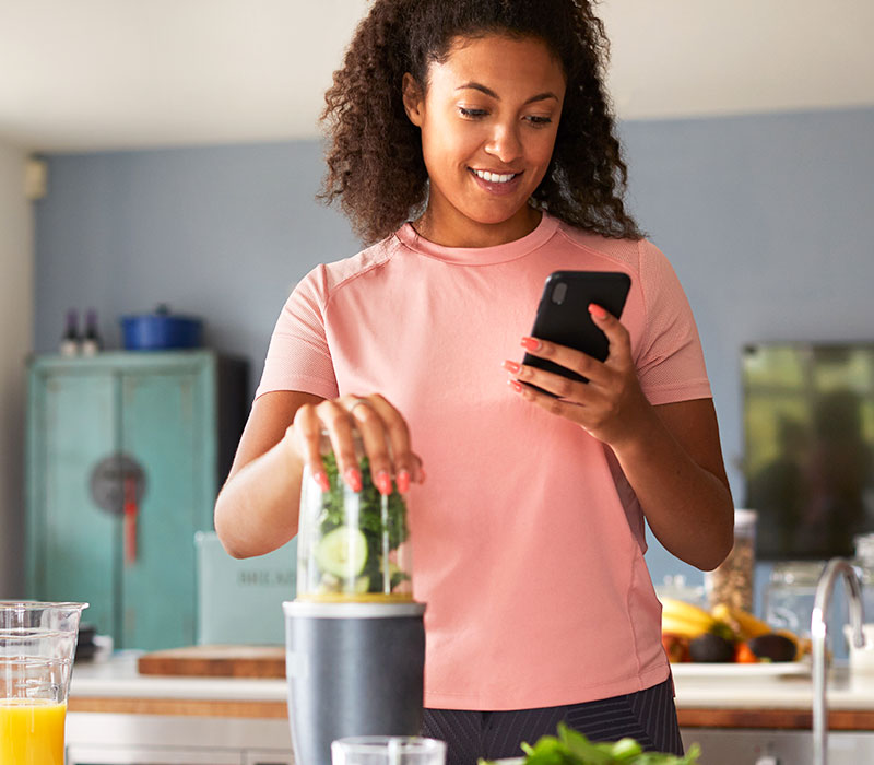 Frau macht Smoothie nach Fitness App