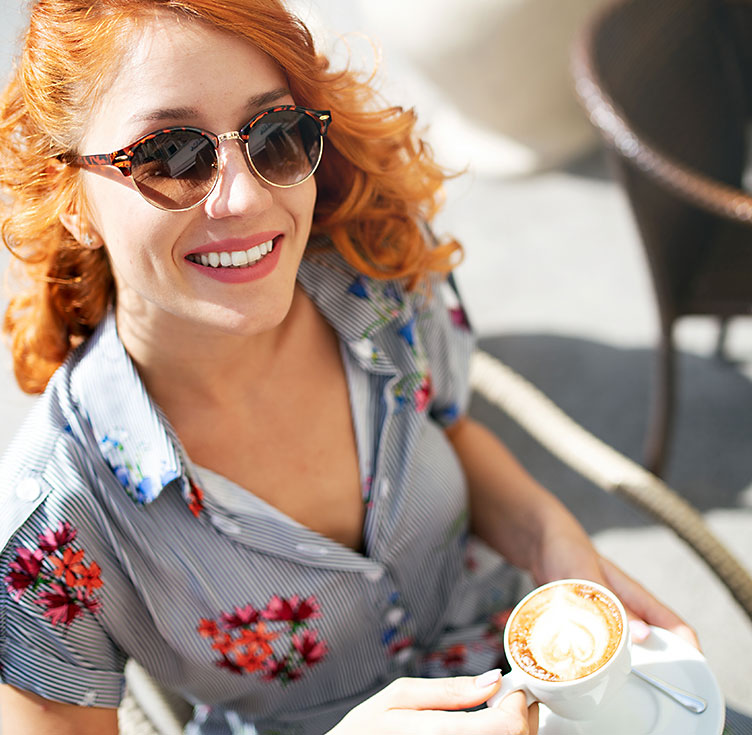 Junge rothaarige Frau freut sich über ihren Milchkaffee