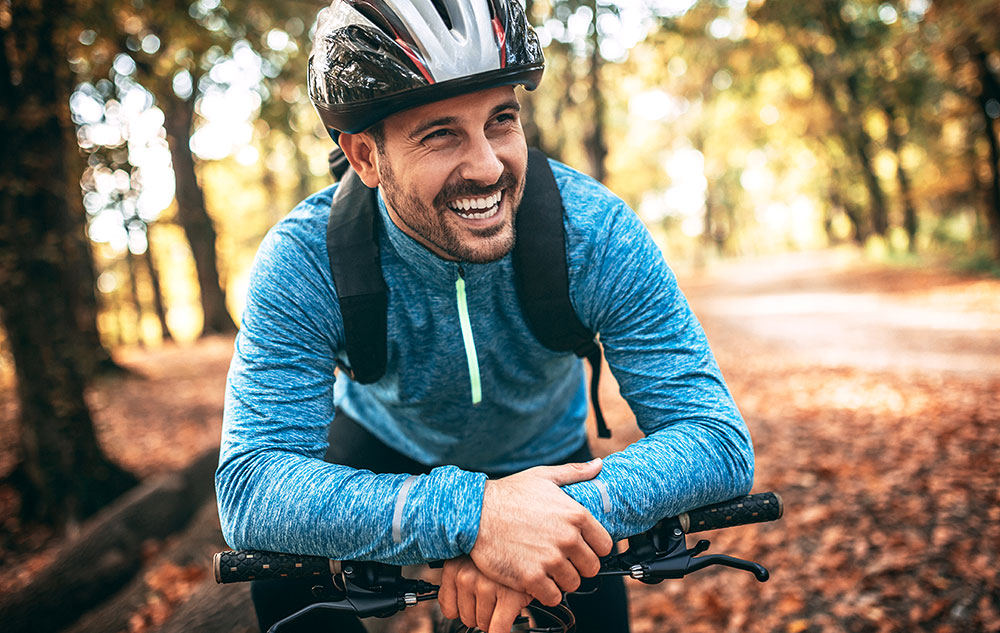 Junger Mann fährt durch Wald mit Mountainbike und macht pause