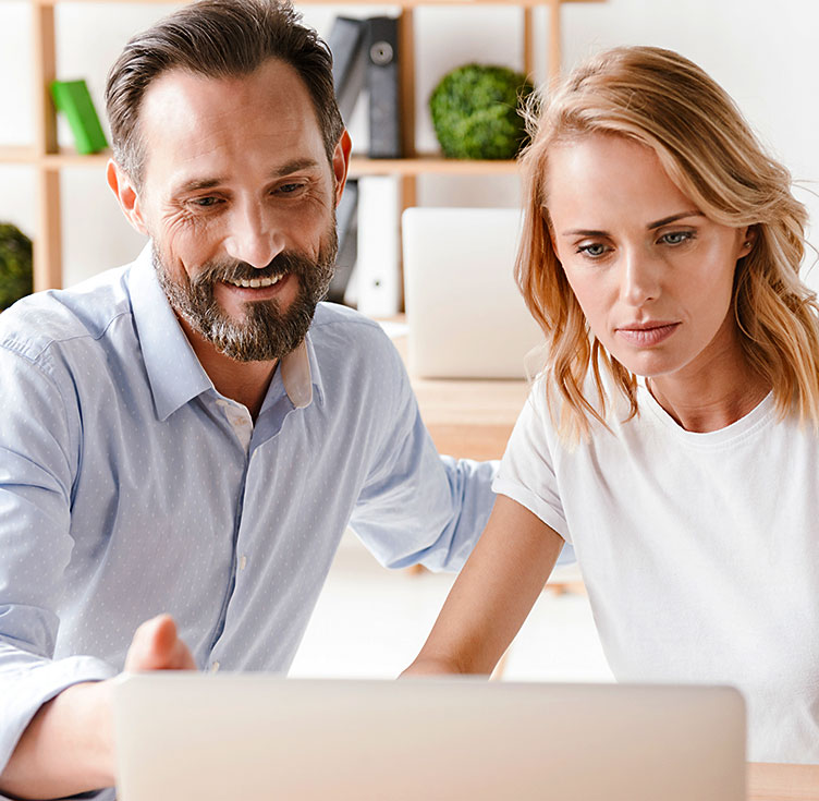 Klientin mit Coach bei Auswertung am Laptop die interessiert schaut