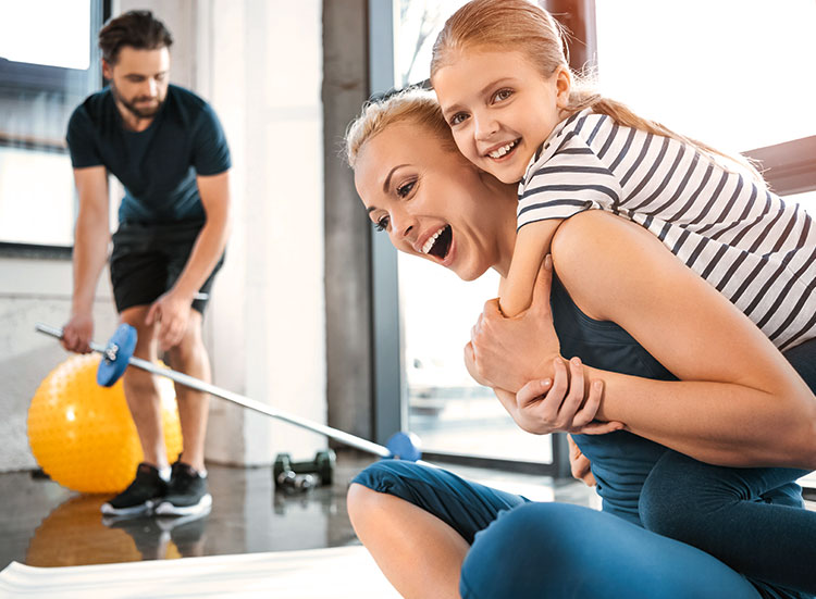 Mädchen umarmt seine Mutter im Fitnessclub beim Sport