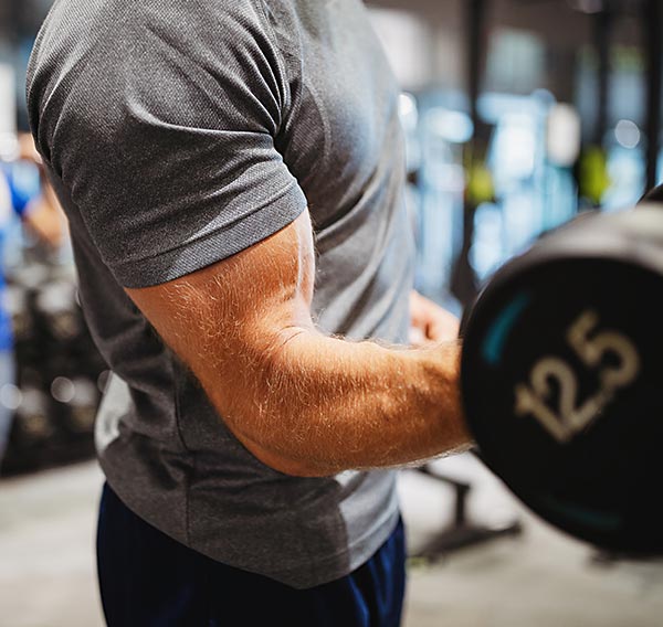 Mann macht Bizepscurl mit Kurzhantel im Gym