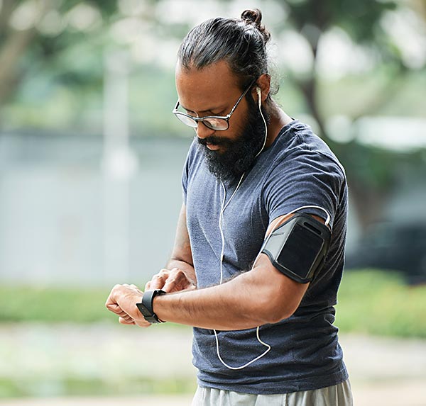 Mann mittleren Alters schaut auf Fitnessuhr und kontrolliert sein Training