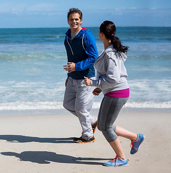 Mittelälteres Paar joggt morgens am Strand