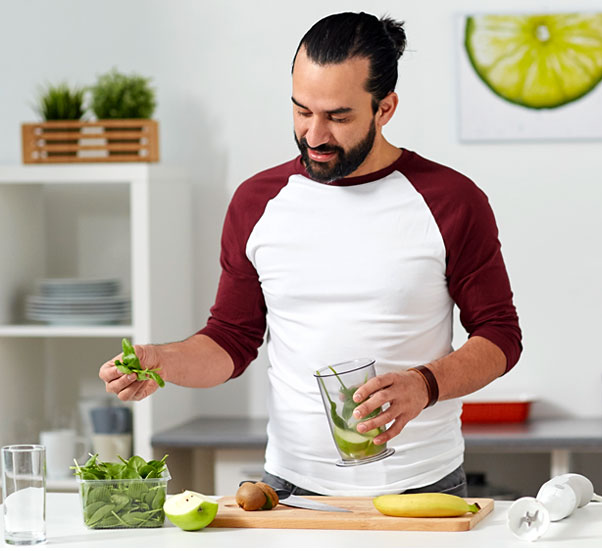 Moderner Mann bereitet grünen Frucht-Smoothie zu