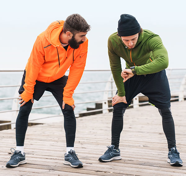 Zwei Jogger auf einem Steg messen ihre Trainingszeit